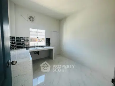 Modern kitchen with sleek black tile backsplash and white marble flooring, featuring a minimalist design.