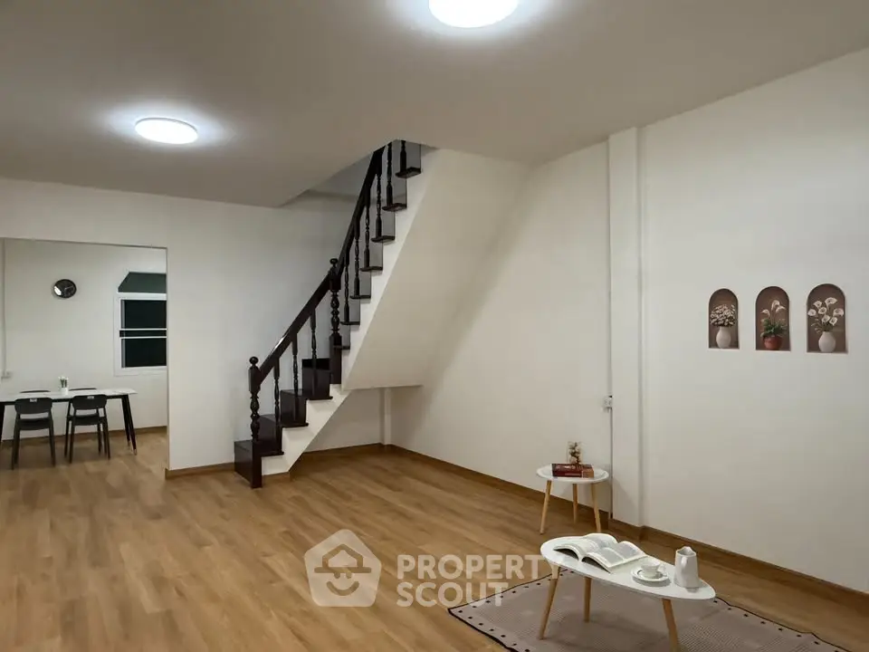 Spacious modern living room with wooden flooring and elegant staircase, perfect for family gatherings.