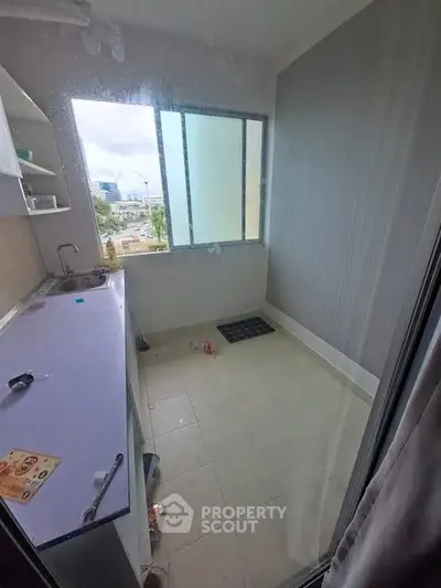 Compact kitchen with window view, featuring minimalistic design and tiled flooring.
