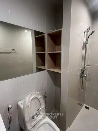 Modern bathroom with sleek shower and storage shelves, featuring contemporary design and neutral tones.