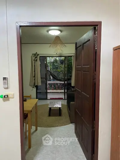 Cozy living room with natural light and garden view, featuring wooden furniture and a welcoming ambiance.