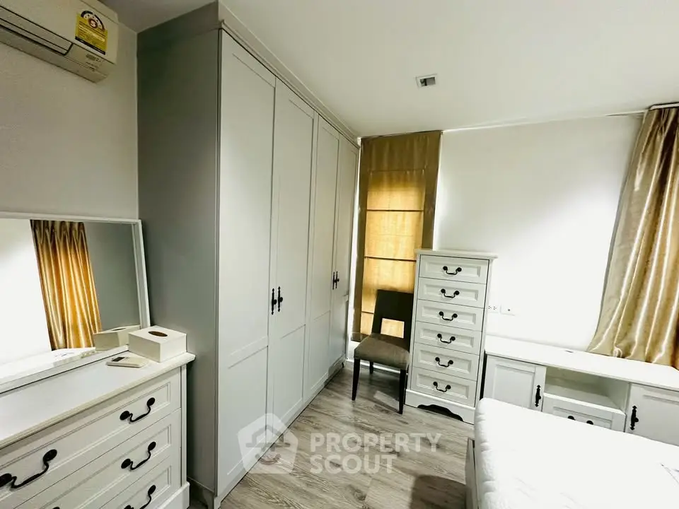 Bright and cozy bedroom with elegant white furniture and ample storage space.