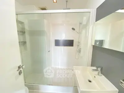 Sleek modern bathroom with glass-enclosed shower, white vanity, and stylish fixtures, perfect for a contemporary home.