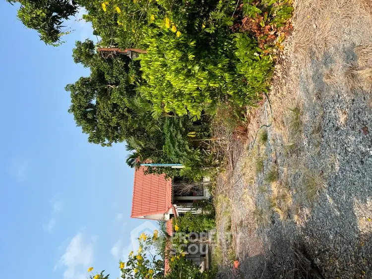 Charming countryside property with lush greenery and red-roofed house, perfect for nature lovers.