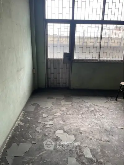 Spacious room with large windows and natural light, ideal for renovation.