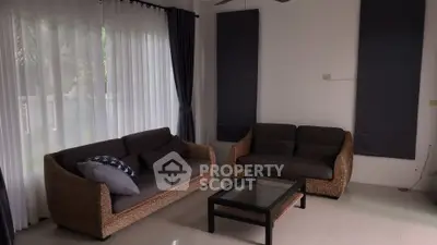 Cozy living room with wicker sofas and glass coffee table, perfect for relaxation.