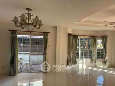 Spacious living room with elegant chandelier and large windows for natural light.