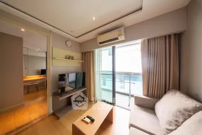 Modern living room with balcony access, featuring cozy sofa and wall-mounted TV in a bright, airy space.
