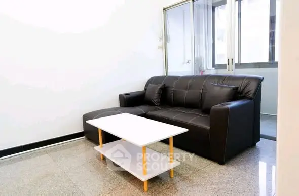 Modern living room with sleek black leather sofa and minimalist coffee table.