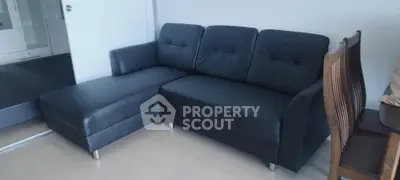 Modern living room with sleek black sofa and elegant wooden dining chairs