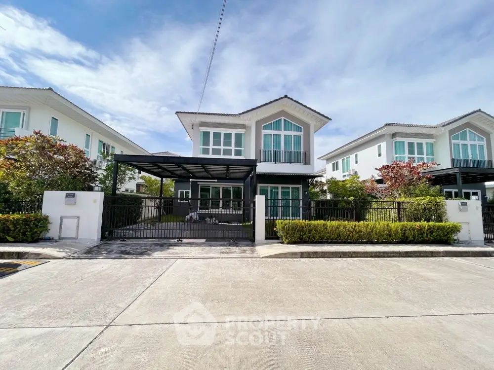 Modern two-story house with large windows and driveway in a suburban neighborhood.