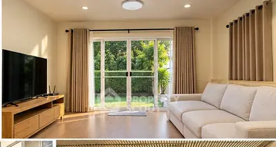 Spacious living room with large windows and modern decor, perfect for relaxation and entertainment.