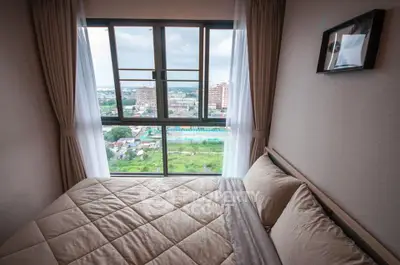 Cozy bedroom with a stunning city view from a high-rise window, featuring elegant curtains and a comfortable bed.