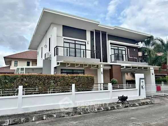 Modern two-story house with sleek design and spacious balcony in a suburban neighborhood.