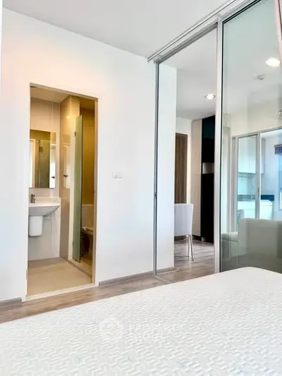 Modern bedroom with ensuite bathroom and sliding glass doors in a stylish apartment.
