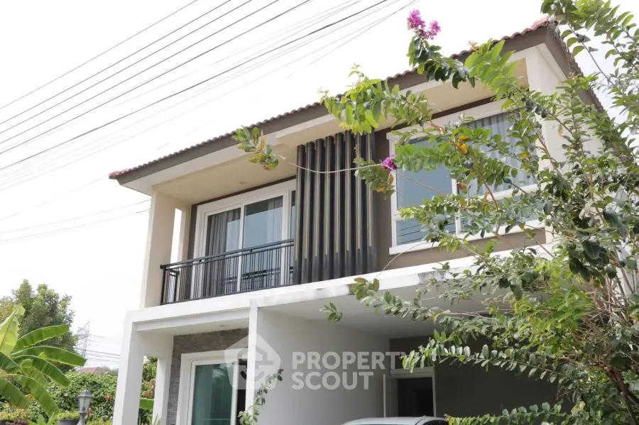 Charming two-story house with balcony and lush greenery, perfect for modern family living.