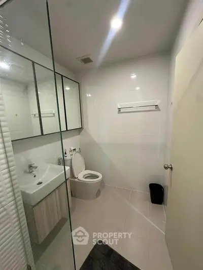 Modern bathroom with sleek fixtures and glass shower enclosure in a contemporary apartment.
