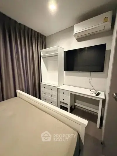 Cozy bedroom with modern furniture and wall-mounted TV, perfect for relaxation.