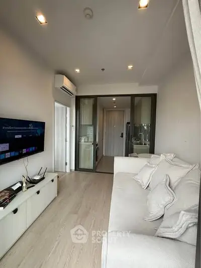 Modern living room with sleek design and glass partition, featuring a cozy sofa and wall-mounted TV.