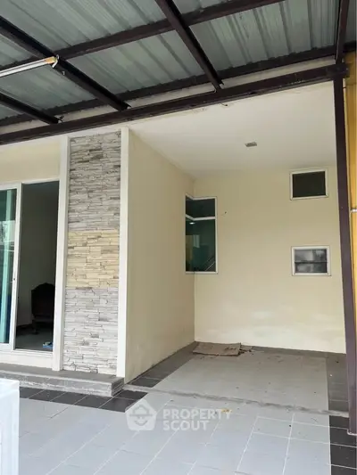 Modern covered entrance with stone accent wall and sliding glass door