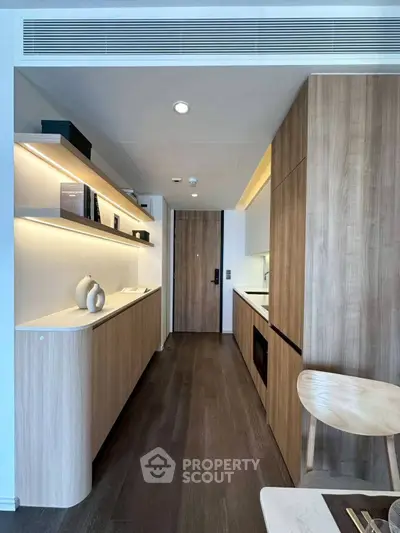 Modern kitchen with sleek wooden cabinetry and integrated appliances in a stylish apartment.