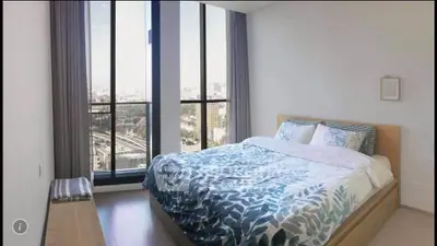 Modern bedroom with large windows offering stunning city views, featuring a cozy bed with stylish bedding.