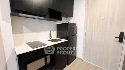 Modern compact kitchen with sleek black cabinets and appliances