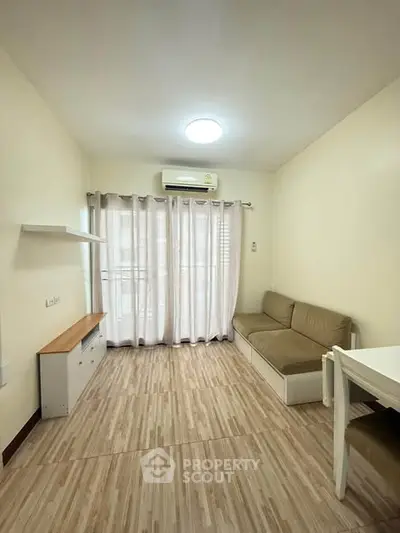 Cozy living room with natural light, wooden flooring, and modern furniture in a compact apartment.
