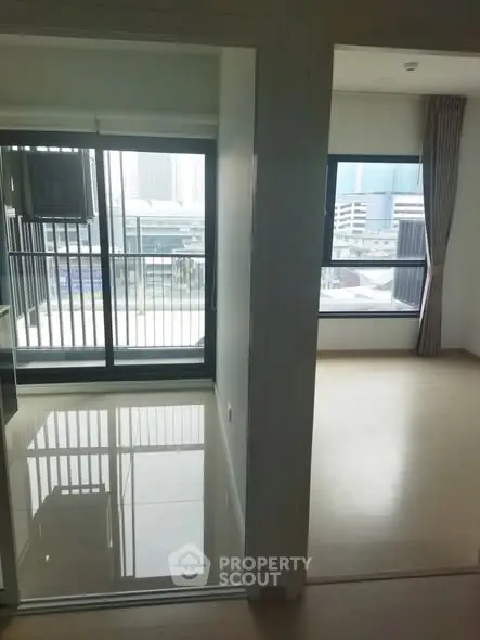 Modern apartment with balcony and city view, featuring sleek flooring and large windows.