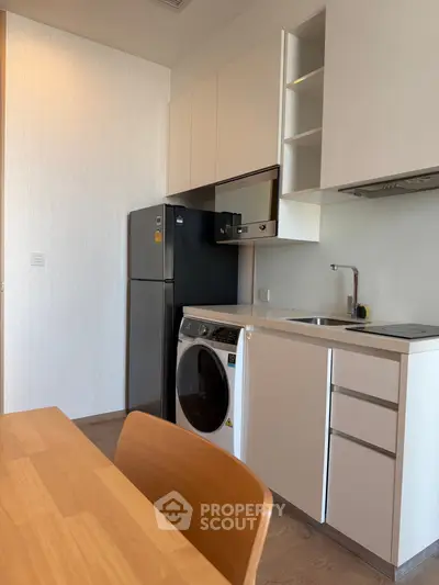 Modern kitchen with sleek appliances and compact design, featuring a washing machine and fridge.