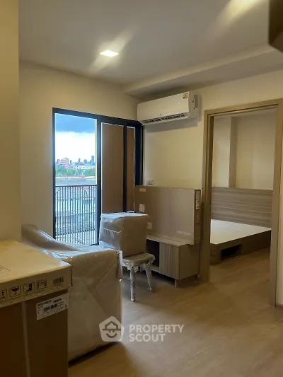 Modern apartment interior with balcony view and air conditioning, featuring a cozy living space and bedroom access.