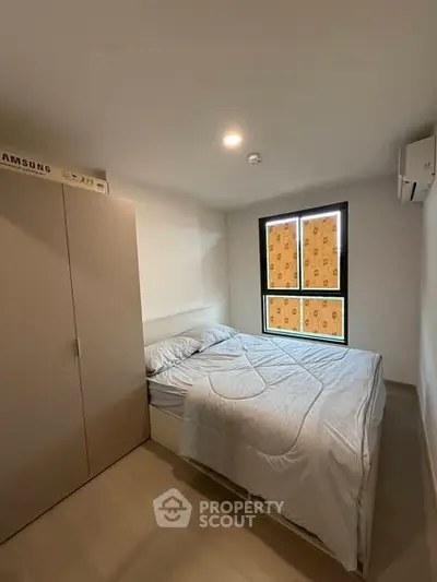Cozy bedroom with modern furnishings and natural light from window.