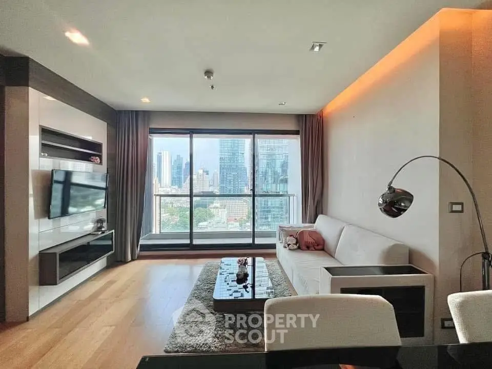 Modern living room with city view, sleek furniture, and large windows in a high-rise apartment.