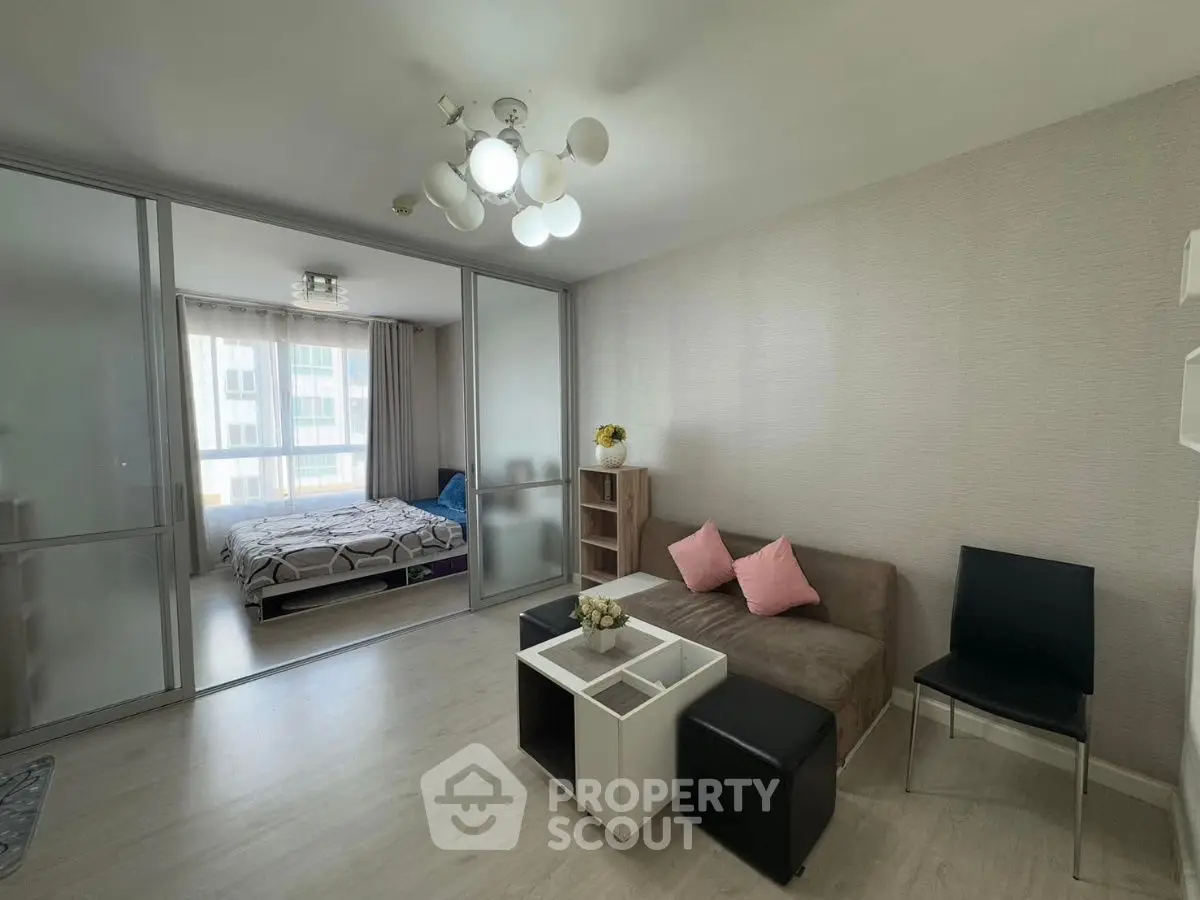 Modern living room with sliding glass doors leading to a cozy bedroom, featuring stylish decor and ample natural light.