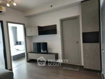 Modern living room with sleek furniture and adjacent bedroom in a stylish apartment.