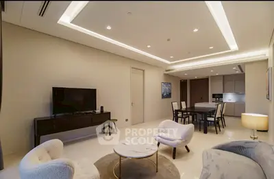 Modern living room with elegant furniture and open kitchen layout, featuring stylish lighting and neutral tones.