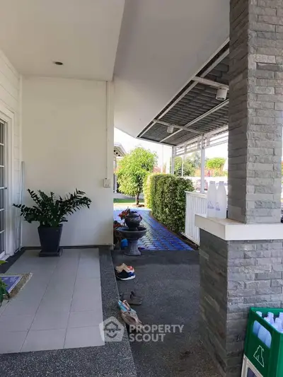 Charming home entrance with covered patio and lush greenery, perfect for relaxation and outdoor enjoyment.