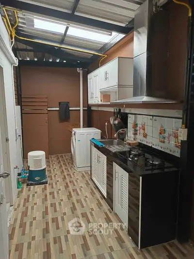 Modern kitchen with gas stove and washing machine in a compact layout.