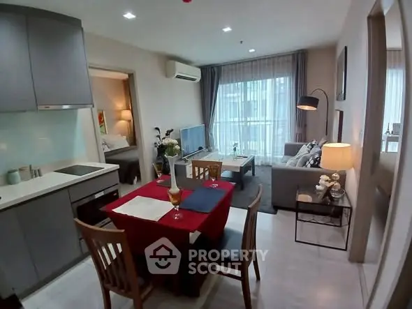 Modern open-plan living room with kitchen and dining area, featuring stylish decor and ample natural light.