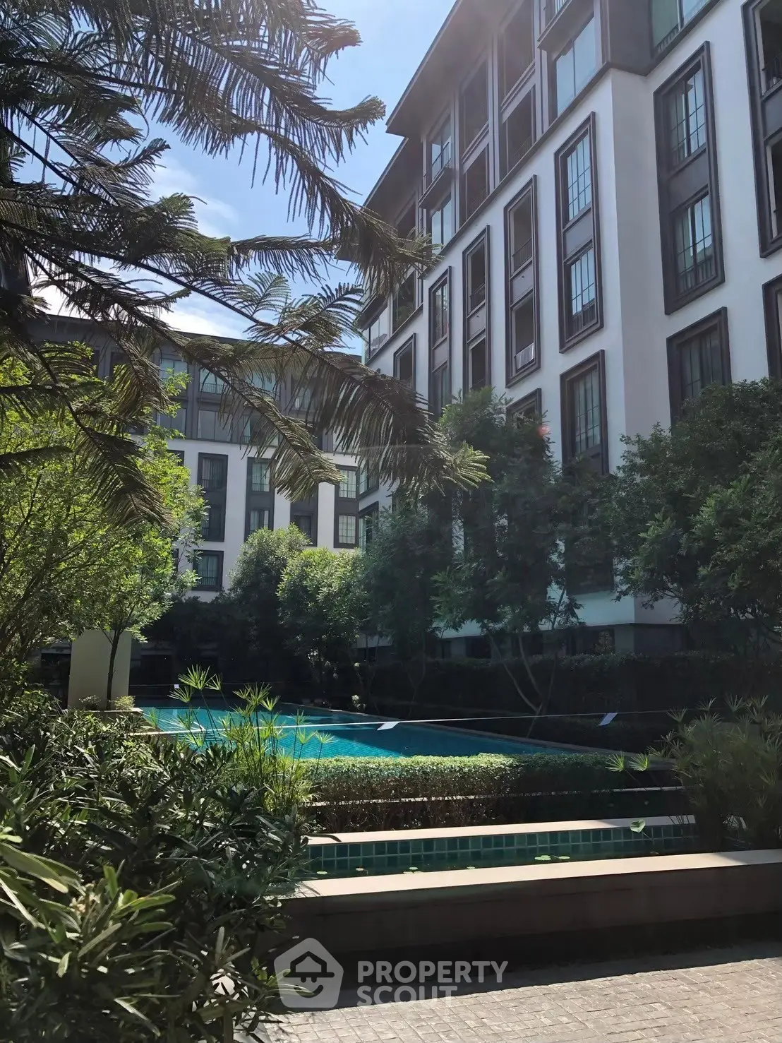 Luxurious residential building with lush greenery and inviting swimming pool