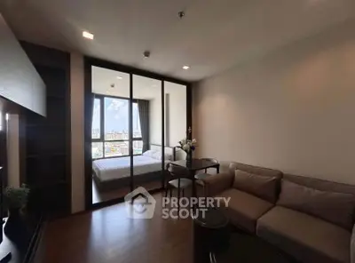 Modern living room with cozy sofa and glass partition leading to a bright bedroom with city view.