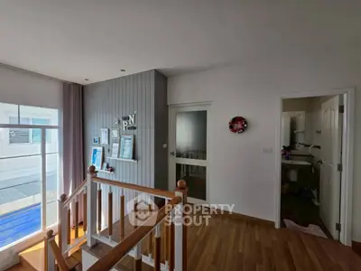 Charming interior hallway with wooden flooring and natural light, featuring a staircase and modern decor.