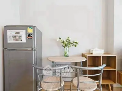 Modern kitchen with sleek fridge and stylish dining set in cozy apartment.