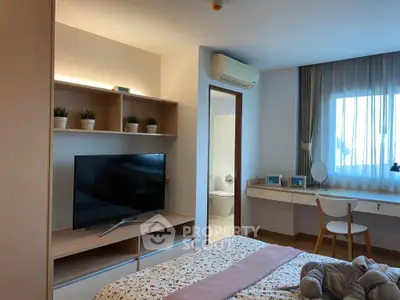 Cozy bedroom with modern decor, featuring a TV, air conditioning, and a window with natural light.