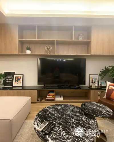 Cozy living room with modern wooden entertainment unit, large TV, and stylish marble coffee table, perfect for relaxing evenings.