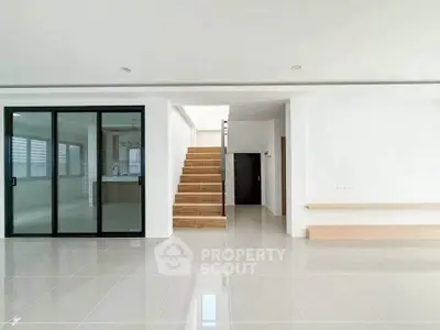 Spacious modern living room with sleek tile flooring and wooden staircase