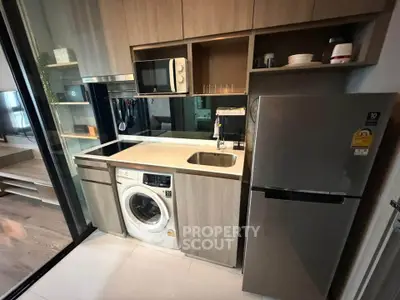 Modern compact kitchen with built-in appliances and sleek cabinetry in urban apartment.