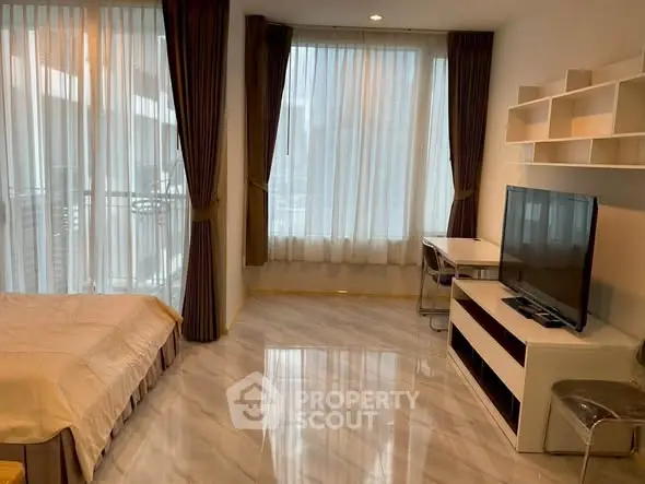 Modern studio apartment with large windows and sleek furnishings in a high-rise building.