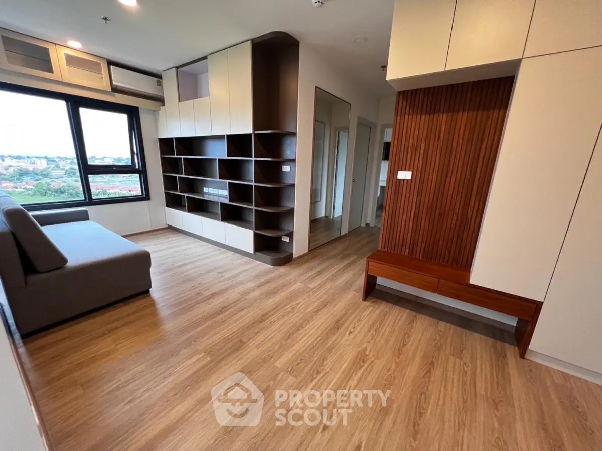 Spacious modern living room with wooden flooring and built-in shelving, offering a cozy and stylish ambiance.