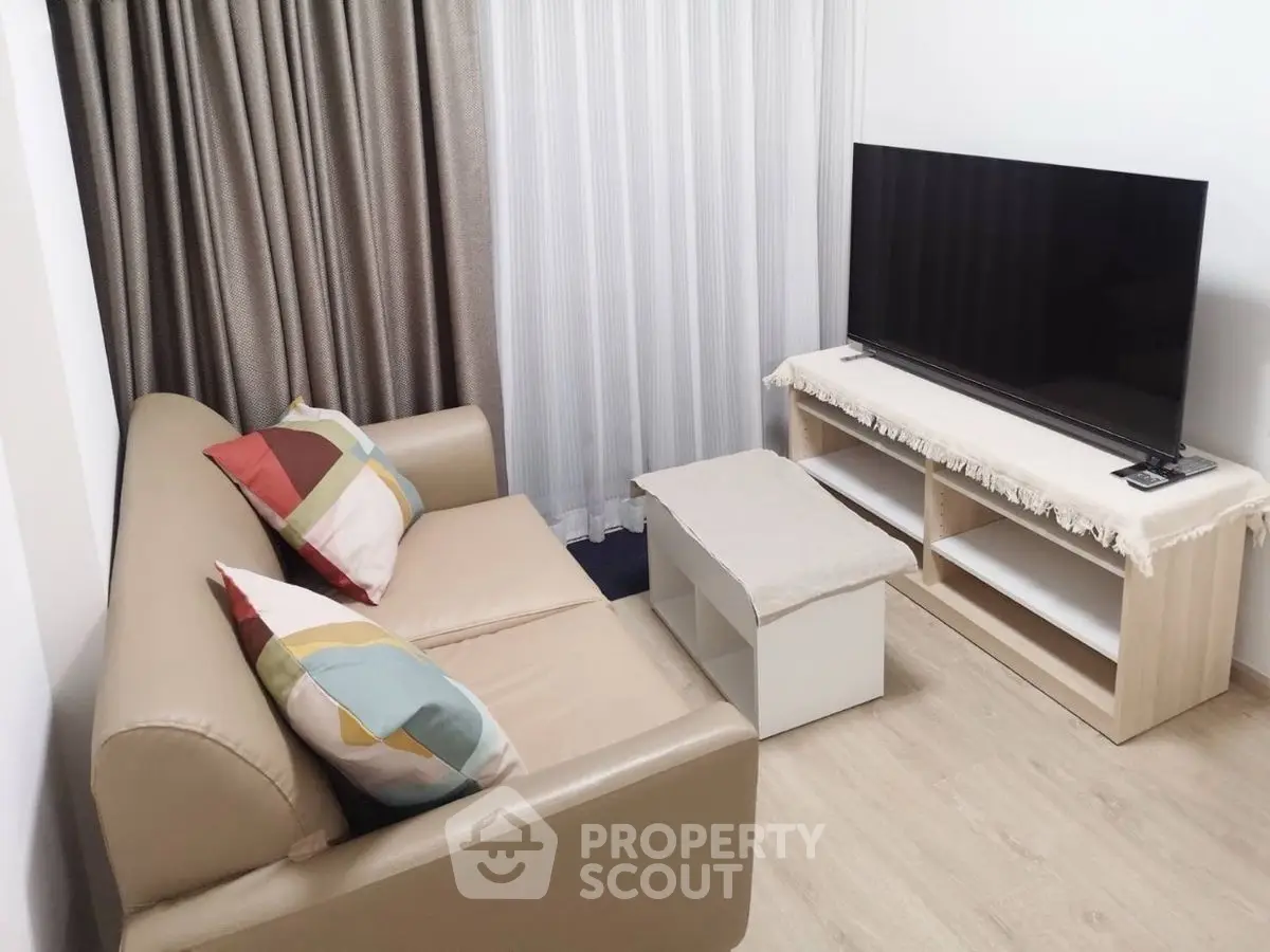 Cozy living room with modern sofa and large flat-screen TV, perfect for relaxation.